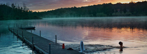 A swimmer in a lake at sunset