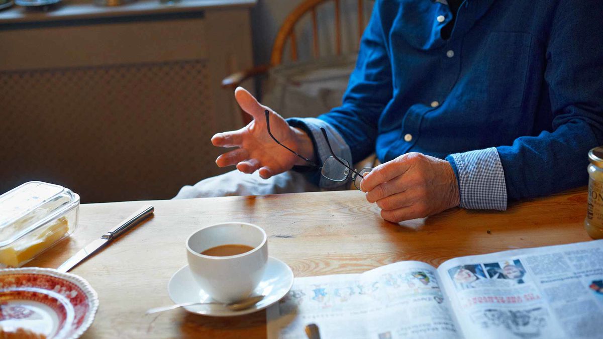 A man holding his glasses sat at a table