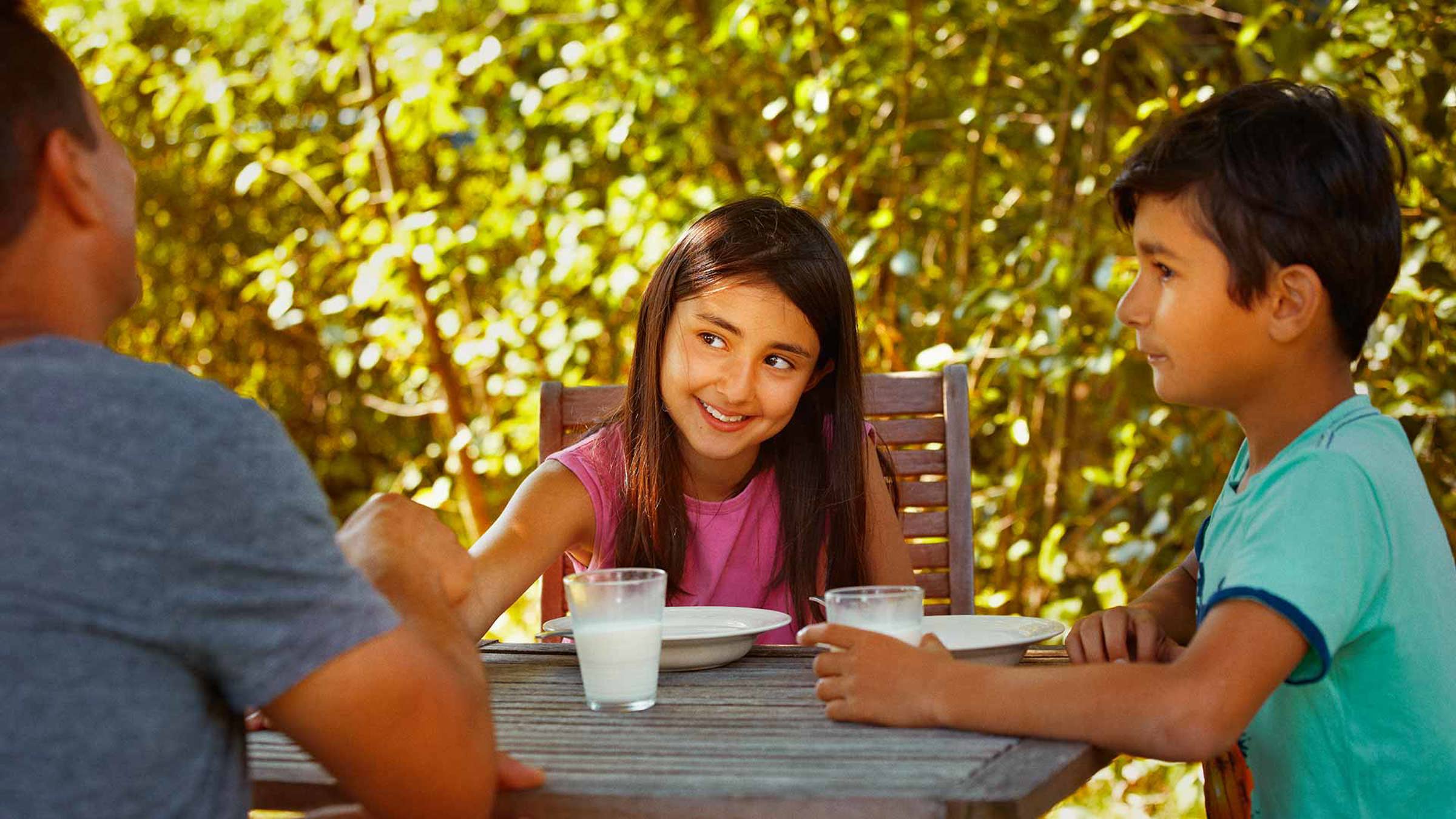 Children smiling at an outdoor dinner table