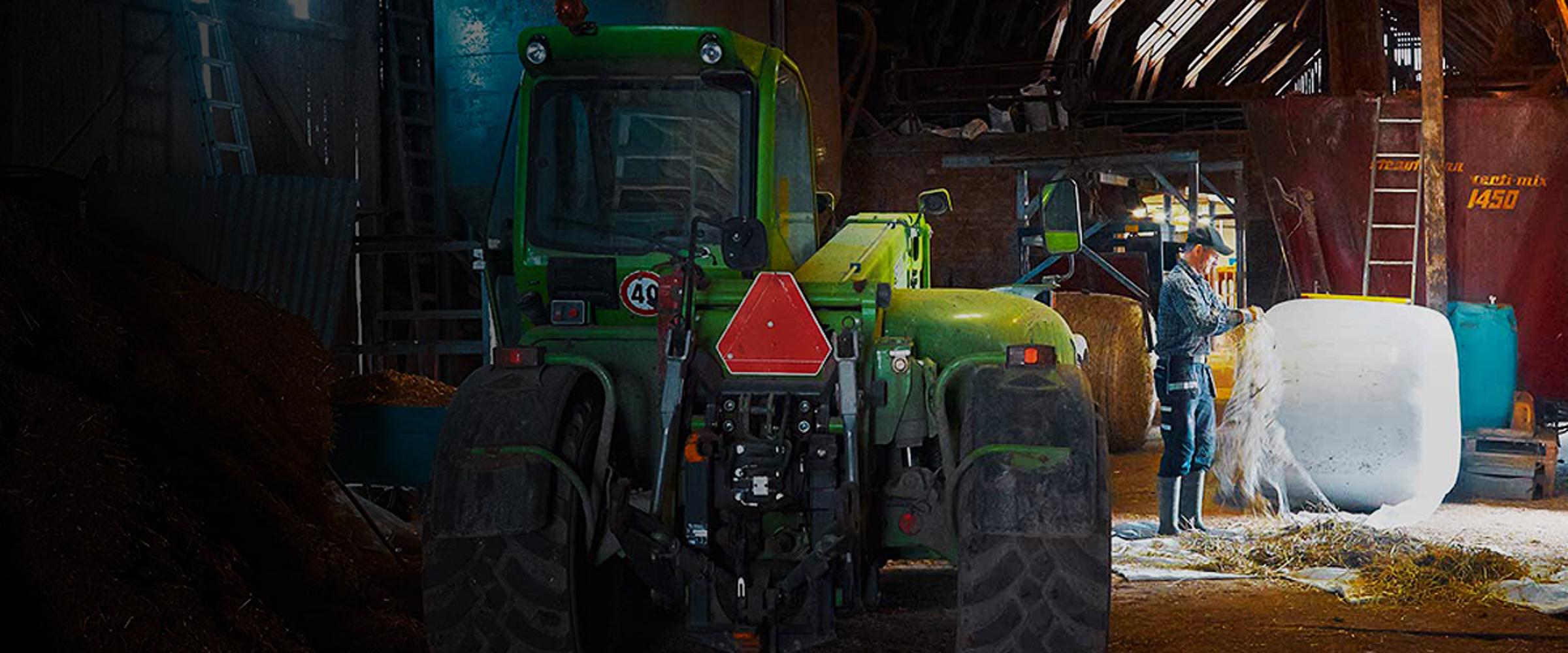 A farmer next to his tractor in a barn