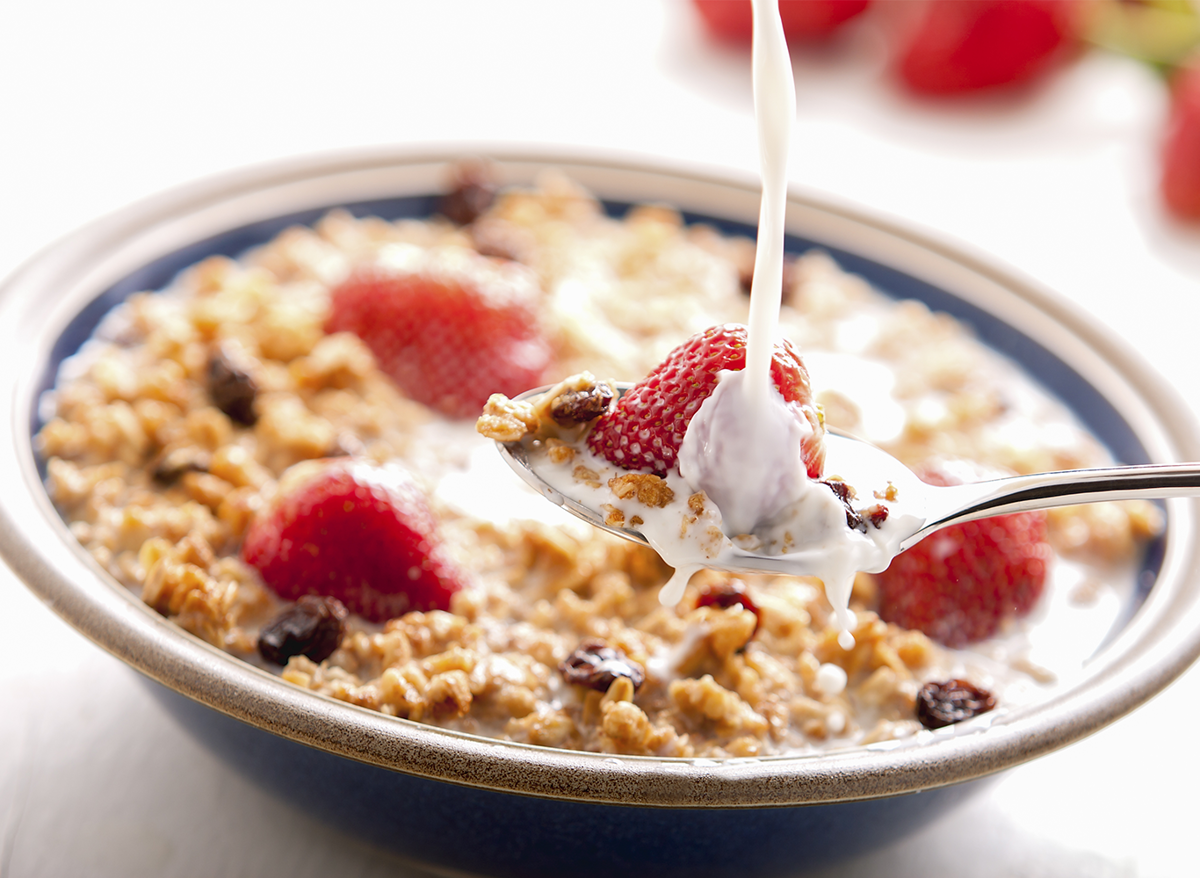 A bowl of oats with milk, raisins and strawberries