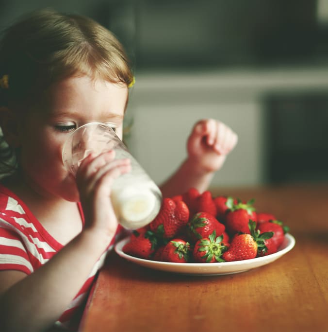 Image of child drinking milk with strawberries