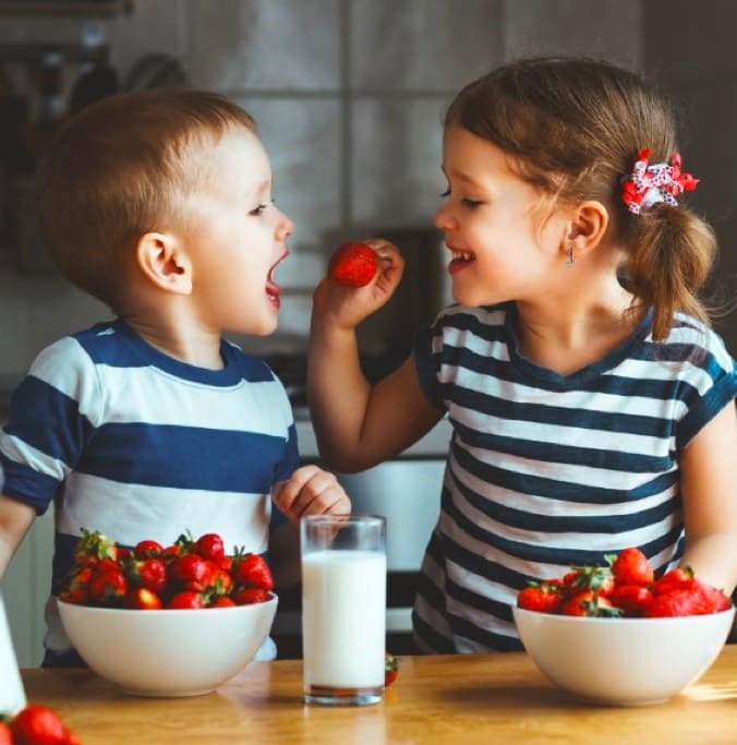 Image of two children eating strawberries